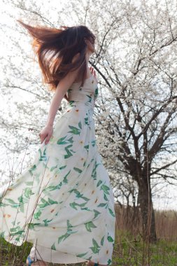 mavi gözlü parlak güneşin altında dinamik bir rüzgarda tam büyüme çiçek bahçesinde ince kahverengi saçlı kadın