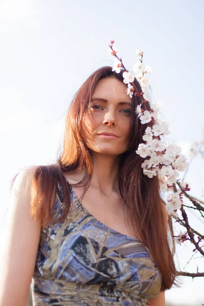 咲く庭に青い目と茶色の髪の女性のクローズ アップの肖像画 — ストック写真