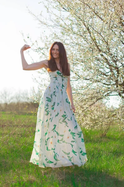 ince sportif kahverengi saçlı mavi gözlü parlak güneş ışığı tam büyüme çiçekli bahçesinde gösterir güçlü bir pazı