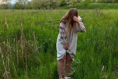 Nakış seductively yeşil bahar çayır üzerinde poz ile keten uzun gömlekli Ukraynalı kız