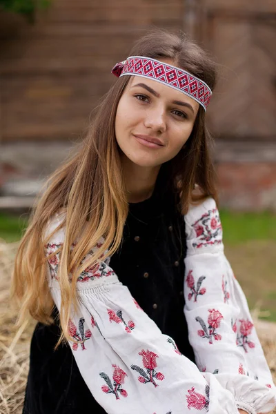 Beautiful Ukrainian woman dressed in embroidery sitting on a wooden cart