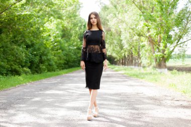 Eski yol asfalt üzerinde şık siyah giysili güzel ince Ukraynalı kadın