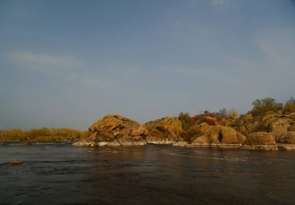 石头在一条快速的河流在秋天的黄色树木在岸边 — 图库照片