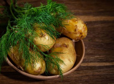 Tahta zemin üzerinde dereotu olan bir tabakta çiğ patates.