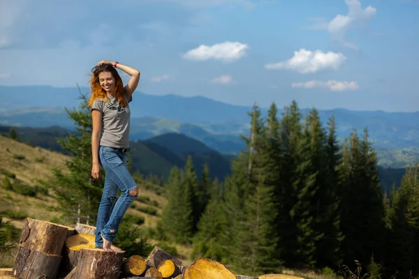 Tişörtlü ve kot pantolonlu bir kız yazın Karpatya dağlarında poz veriyor.