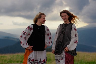 Ukrayna 'da işlemeli iki duygusal neşeli kız yazın Karpatya dağlarında yüksek elbiseler