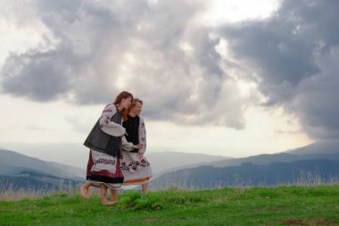 Ukrayna 'da işlemeli iki duygusal neşeli kız yazın Karpatya dağlarında yüksek elbiseler