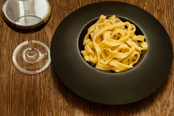 Italiaanse Pasta Geserveerd Een Zwarte Plaat Met Een Glas Wijn — Stockfoto
