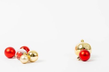 Bir sürü altın ve kırmızı Noel süsleri beyaz arka plana saçılmış. Altın süsler daha büyük ve daha belirgin iken, kırmızı olanlar daha küçük ve daha çoktur.