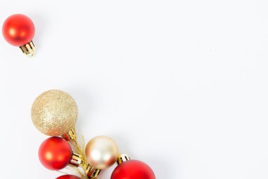 Bir sürü kırmızı ve altın Noel süsleri beyaz arka plana saçılmış. Sahne, süslerin parlak renkleri gibi neşeli ve neşeli bir havayı yansıtıyor.