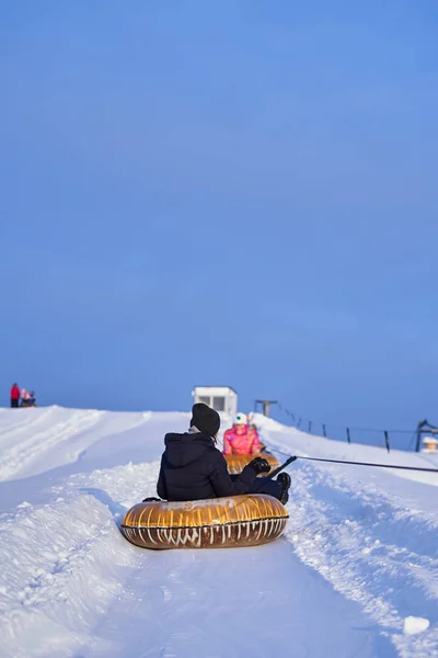 En jente som rir på slanger fra et snødekt fjell om vinteren. – stockfoto