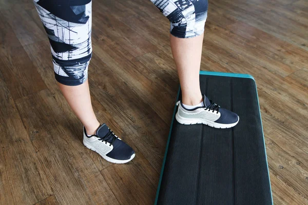 legs of a girl on a shell step in the gym