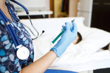 Doktor bir yatağı-hasta hasta evde arka planda bir çözüm bir şırınga tutar