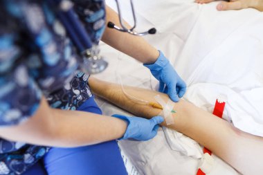 Hemşire hastanın el enjeksiyon için hazırlar. Hasta beyaz yatak çarşafları ile kanepede yatıyor