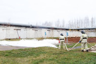 İtfaiye itfaiye uzun bir hortum aracılığıyla gelen bir kimyasal köpük ile yangın söndürmek