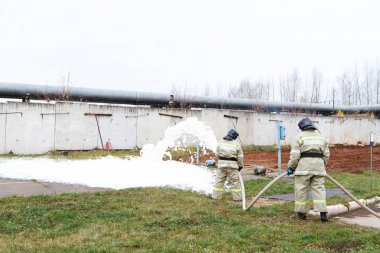 İtfaiye itfaiye uzun bir hortum aracılığıyla gelen bir kimyasal köpük ile yangın söndürmek