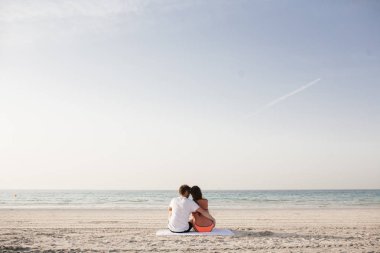 Deniz kıyısı üzerinde birlikte oturan güzel Çift