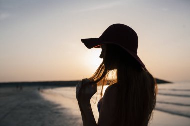 Gün batımı bir arka plan üzerinde bir kumsalı güzel kız. Kadın.