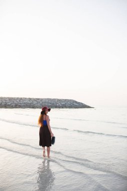 Güzel bir kız ve kıyı günbatımı karşı yürüyor