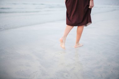 Güzel bir kız ve kıyı günbatımı karşı yürüyor