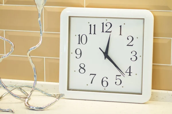 A clock with a lamp on a white table in a cosmetology cabinet