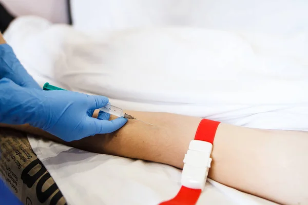 A nurse prepares to inject injection needles into a patient lying on the couch