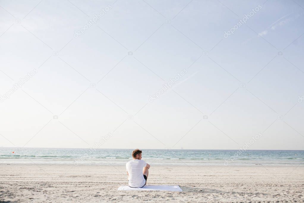 the man is sitting on the seashore alone
