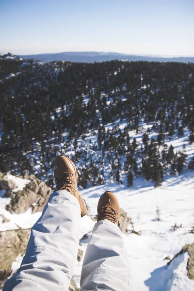 Le gambe della ragazza pendono sullo sfondo di montagne e foreste — Foto Stock