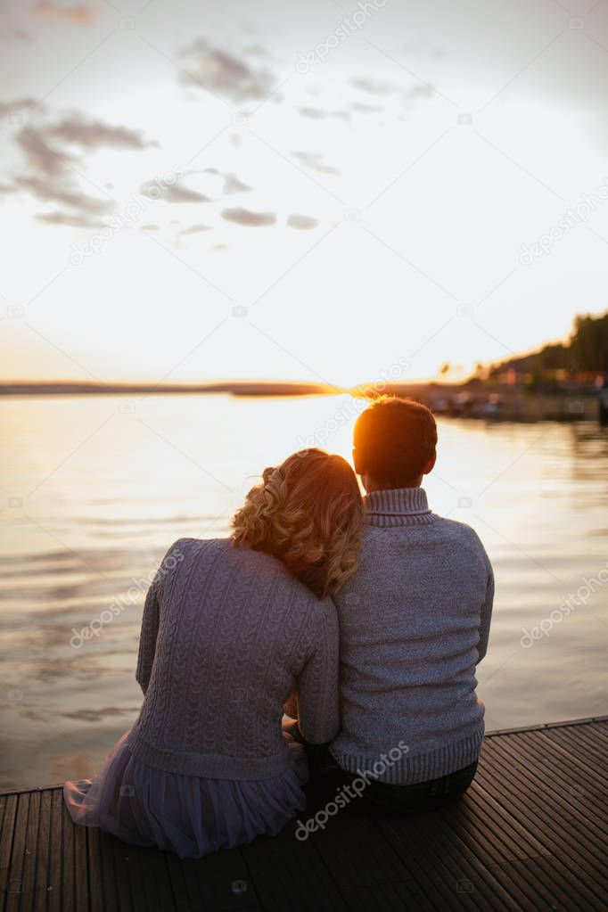 Girl and man sit on the edge of the lake and look into the distance