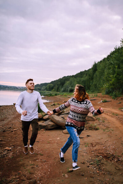 Young couple having fun and running along the river