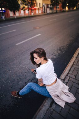Kız yolun kenarında oturuyor. Sokak kentsel tarzı.