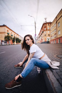 Kız yolun kenarında oturuyor. Sokak kentsel tarzı.