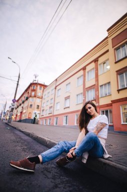 Kız yolun kenarında oturuyor. Sokak kentsel tarzı.