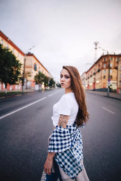 A rapariga virou-se no meio da estrada. Menina em uma camisa xadrez e jeans . — Fotografia de Stock