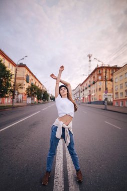 Yolun ortasında poz veren kız. Şık giysi ve şapka kız.