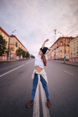 Yolun ortasında poz veren kız. Şık giysi ve şapka kız.