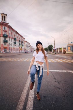 Yolun ortasında poz veren kız. Şık giysi ve şapka kız.