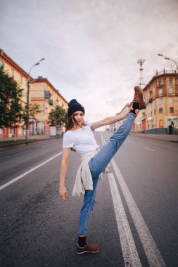 Yolun ortasında poz veren kız. Şık giysi ve şapka kız.