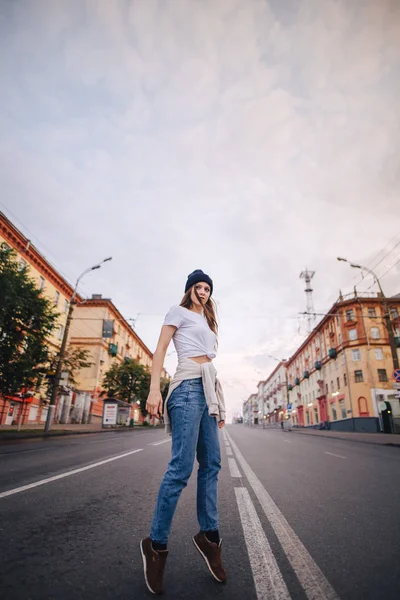 Yolun ortasında poz veren kız. Şık giysi ve şapka kız.