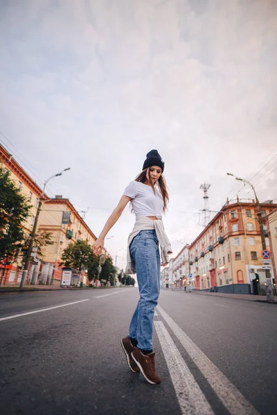 Yolun ortasında poz veren kız. Şık giysi ve şapka kız.