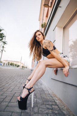 Yüksek topuklu kız şehrin sokaklarında poz. Siyah üst ve kısa şort kız.