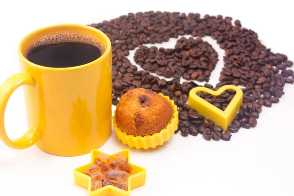 Bir fincan kahve, biraz esmer şeker, kek ve arka planda beyaz üzerine bir kahve kalbi.