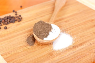 Ahşap kaşık masasında tuz ve biber.