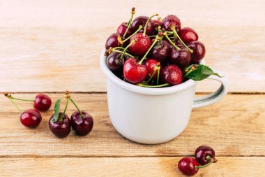bir beyaz emaye kupa üzerinde ahşap bir masa, taze kiraz, mevsim meyveleri, tatlı kiraz, Olgun çilek, kiraz meyveleri bir bardağa