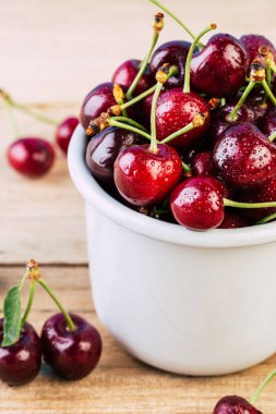 Kiraz ahşap bir masa, taze kiraz, mevsim meyveleri, tatlı çilek, kiraz, Olgun bir beyaz emaye kupa için tanıtıcı içinde çilek