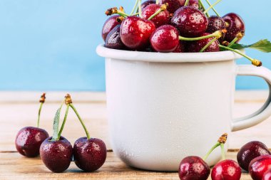 Kiraz ahşap bir masa, taze kiraz, mevsim meyveleri, tatlı çilek, kiraz, Olgun bir beyaz emaye kupa için tanıtıcı içinde çilek