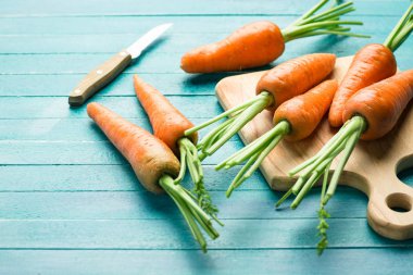 Yönetim Kurulu ve bıçak, taze sebze, karoten kesme mavi ahşap arka plan üzerinde havuç