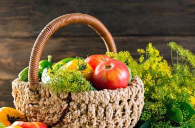 Bir sepet dereotu şemsiye bir ahşap zemin üzerine sarı ve kırmızı domates