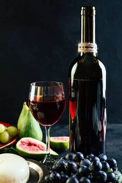 Kırmızı şarap üzüm incir ve siyah arka plan üzerine peynir