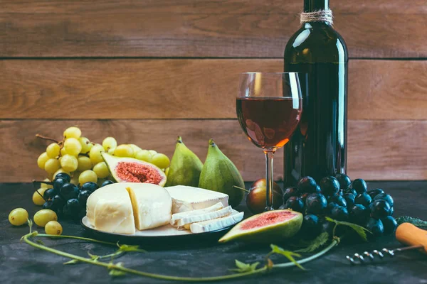 Kırmızı şarap üzüm incir ve siyah arka plan üzerine peynir
